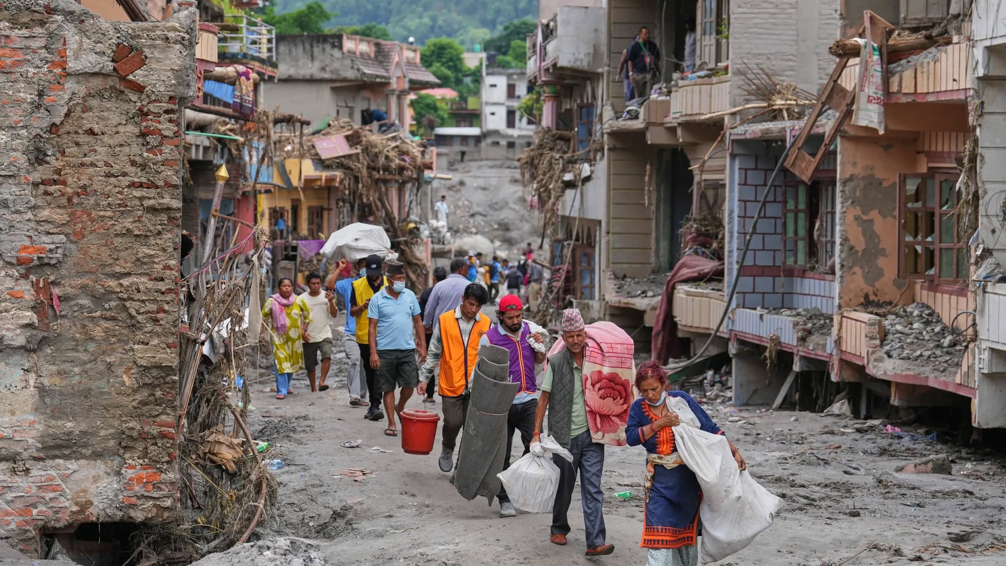 Mensen lopen door een door overstromingen zwaar beschadigde straat in Nepal.